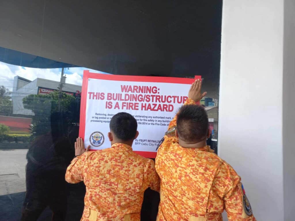 BFP warns Cebu City condo management: Correct violations or else…Personnel of the Bureau of Fire Protection posts a warning sign on the glass wall of a condominium in Barangay Mabolo, Cebu City this afternoon, November 20. | Futch Anthony Inso