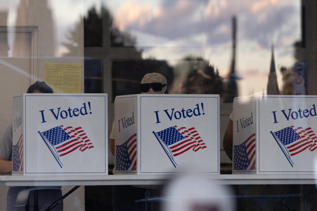 People complete their ballots as the sunset is reflected in the glass of a precinct in the Bloomfield neighborhood of Pittsburgh, Pennsylvania, on November 5, 2024. (Photo by Rebecca DROKE / AFP)