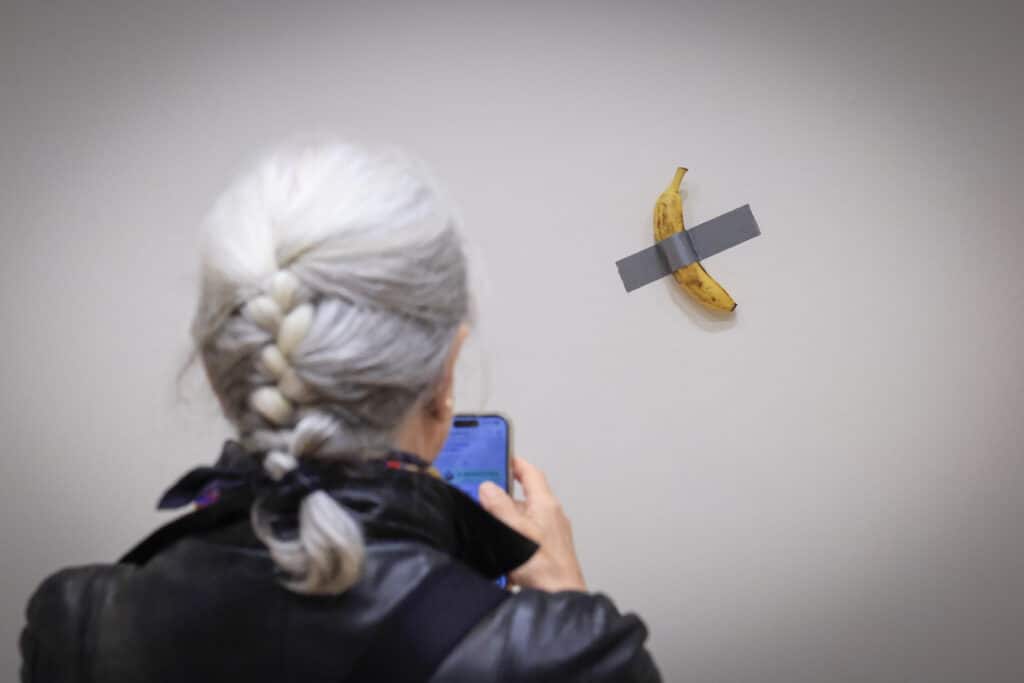 How a viral, duct-taped banana came to be worth $1 million. In photo is a journalist taking a picture of Italian visual artist Maurizio Cattelan's duct-taped Banana entitled "Comedian," displayed during a media preview at Sotheby's in New York, on November 8, 2024. | Photo by kena betancur / AFP