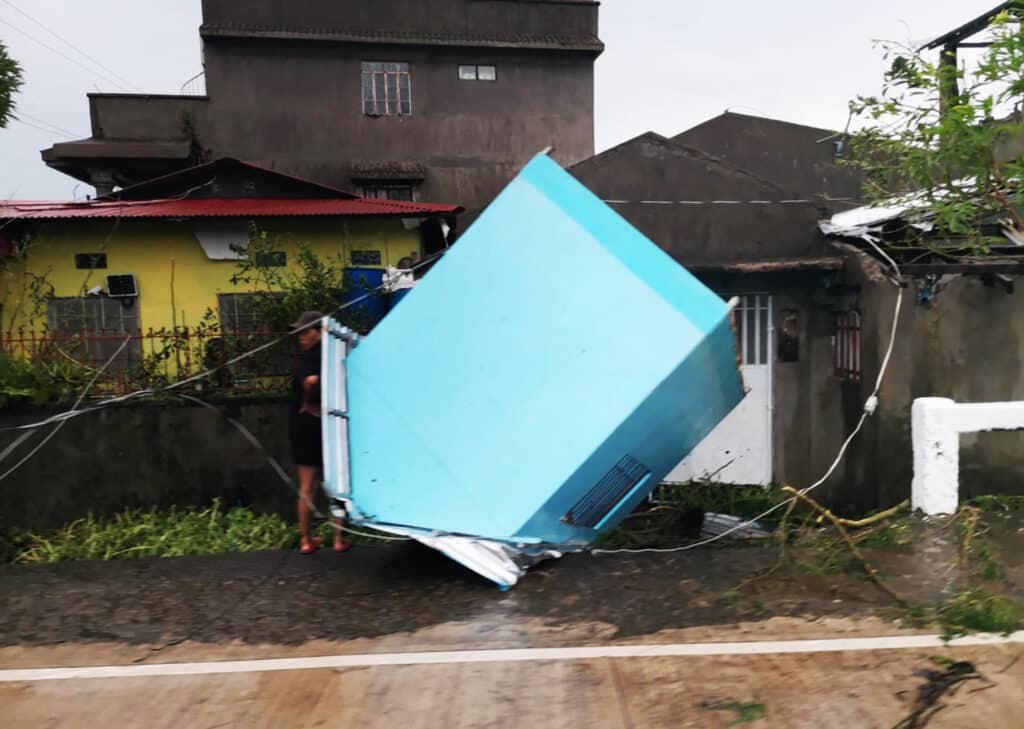 This handout photo released on November 17, 2024 through the courtesy of John Marshal Aquino Facebook page shows a resident standing next to a blown off kiosk along a street in Panganiban town, Catanduanes province, after Super Typhoon Pepito hit the province. | Photo by John Marshal Aquino / John Marshal Aquino / AFP