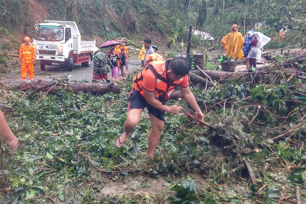 This handout photograph taken and released on November 17, 2024 by the Philippine Coast Guard (PCG) shows coast guard personnel clearing a highway of fallen trees in Gigmoto town, Catanduanes province, south of Manila, after super Typhoon hit the province overnight. | Photo by Philippine Coast Guard (PCG) / AFP