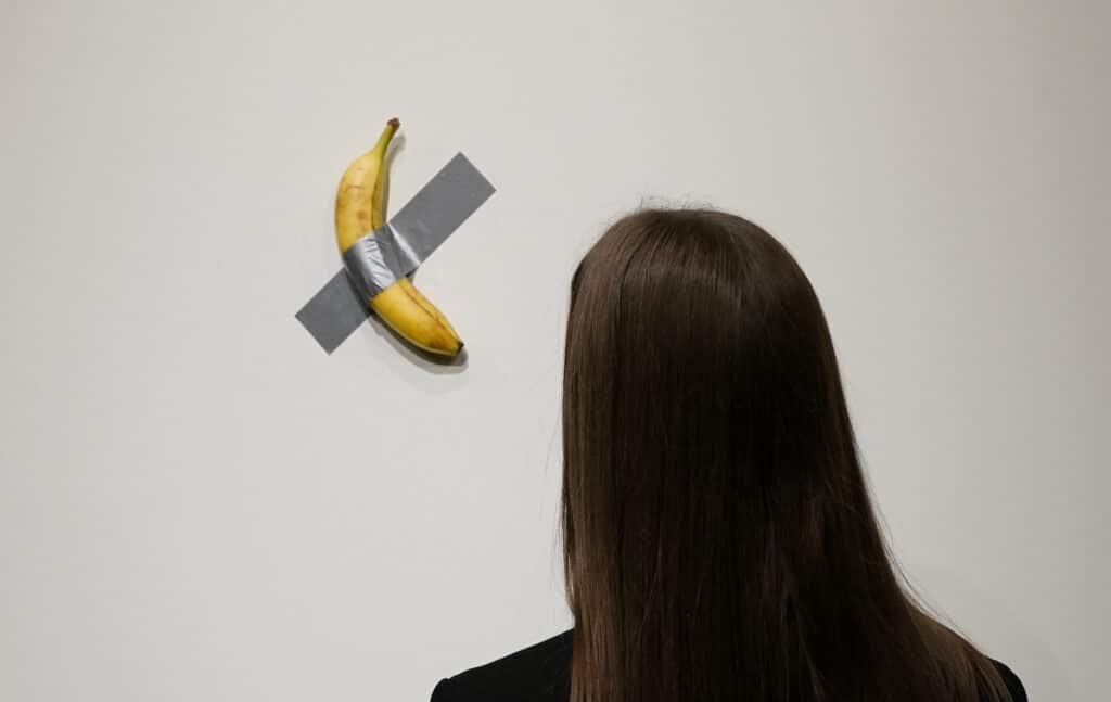 (FILES) People look at Italian visual artist Maurizio Cattelans duct-taped Banana entitled "Comedian," during a press preview at Sotheby's in New York, on October 25, 2024. | Photo by TIMOTHY A. CLARY / AFP