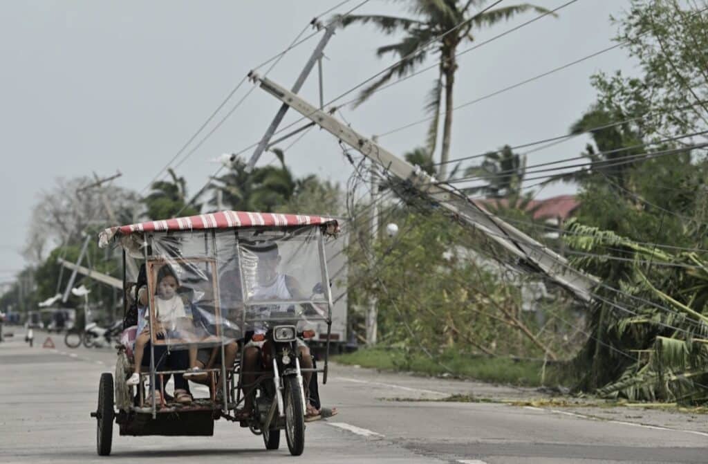 Residents riding a tricycle pass by toppled electrical posts caused by Typhoon Yinxing, locally called Marce, in Camalaniugan, Cagayan province, northern Philippines on Friday Nov. 8, 2024.