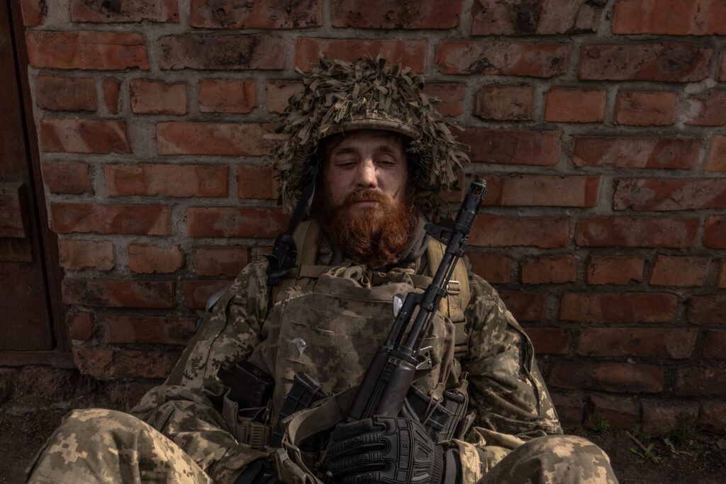 A Ukrainian infantry soldier of the 23rd Mechanized Brigade sits as he waits to deploy toward the frontline in the Avdiivka direction, in the Donetsk region, on April 3, 2024, amid the Russian invasion of Ukraine. | Photo by Roman PILIPEY / AFP