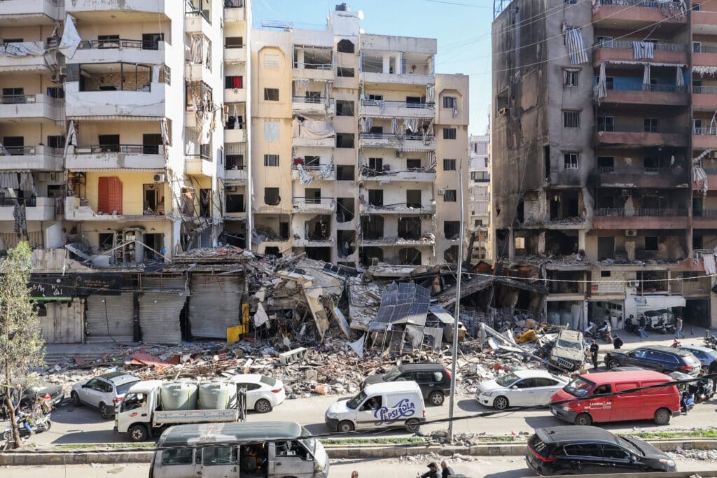 Cars drive past buildings that were damaged or destroyed in Israeli strikes in Beirut's southern suburbs Hay el-Sellom neighbourhood on December 2, 2024. (Photo by Anwar AMRO / AFP)