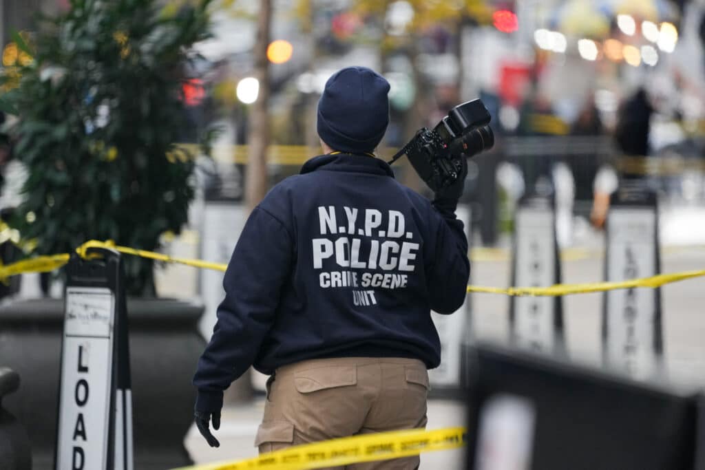 New York killing: CEO shot dead by masked gunman outside hotel. In photo is a Crime Scene Unit officer photographing the scene where CEO of UnitedHealthcare Brian Thompson, 50, was shot and killed as he entered the New York Hilton hotel early on December 4, 2024 in New York. | Photo by Bryan R. SMITH / AFP