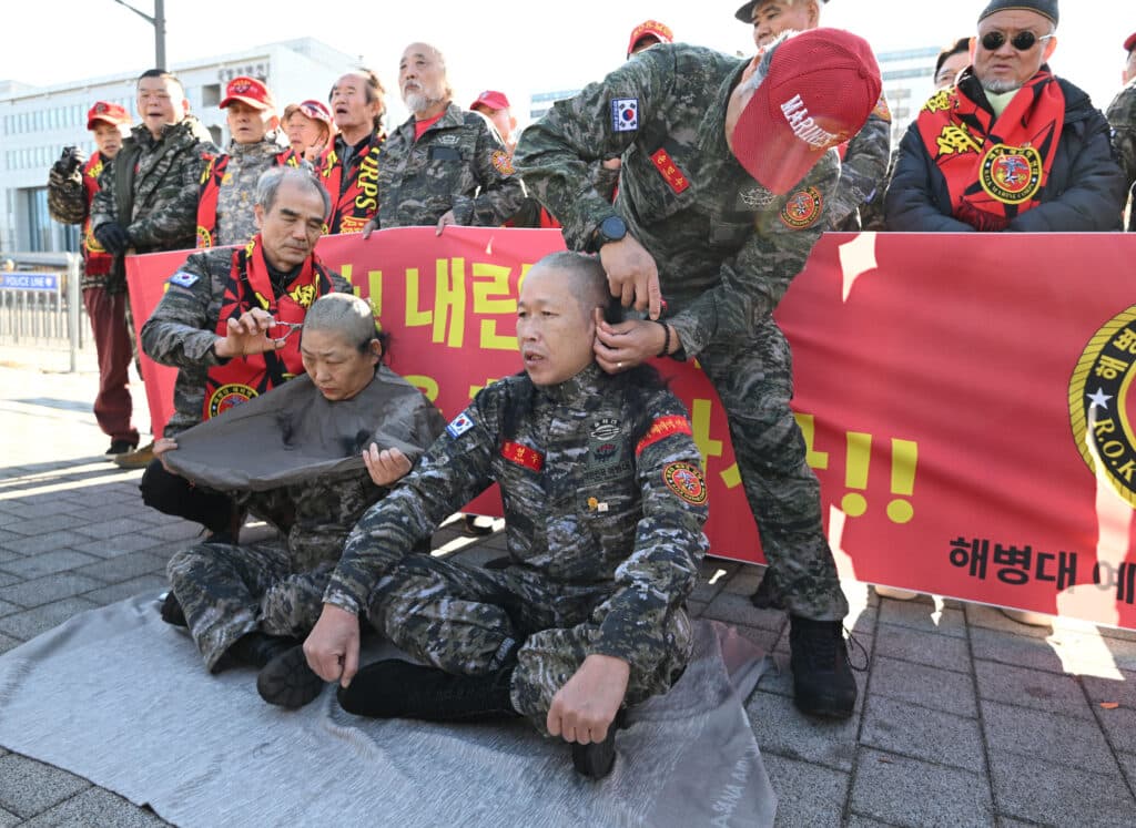 A South Korean marine veteran (R) and his wife (L) get their heads shaved during a protest calling for the resignation of South Korea's President Yoon Suk Yeol near the Presidential Office in Seoul on December 5, 2024. | Photo by JUNG YEON-JE / AFP