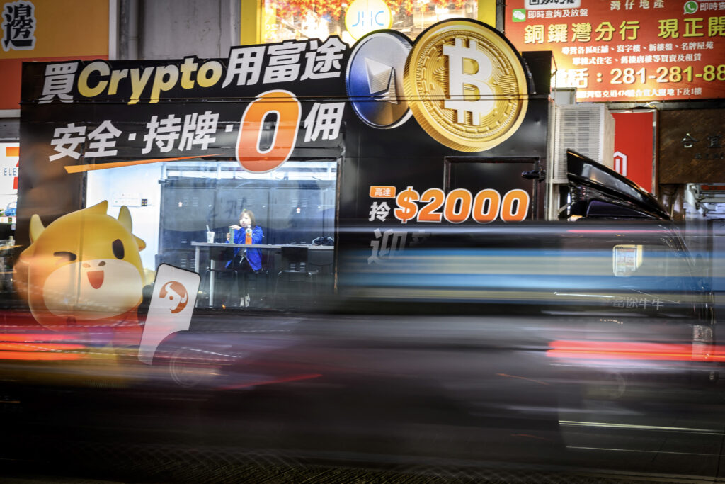 Bitcoin breaks $100,000 for first time, buoyed by Trump's SEC pick. (FILES) An employee sits inside a Bitcoin exchange advertisement truck in Hong Kong on November 27, 2024. | Photo by Mladen ANTONOV / AFP