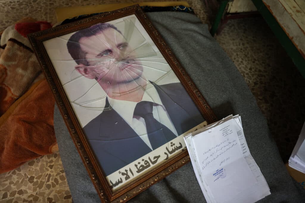 A portrait of Syrian President Bashar al-Assad is pictured with its frame broken, in a Syrian regime's Political Security Branch facility on the outskirts of the central city of Hama, following the capture of the area by anti-government forces, on December 7, 2024 .|Photo by OMAR HAJ KADOUR / AFP