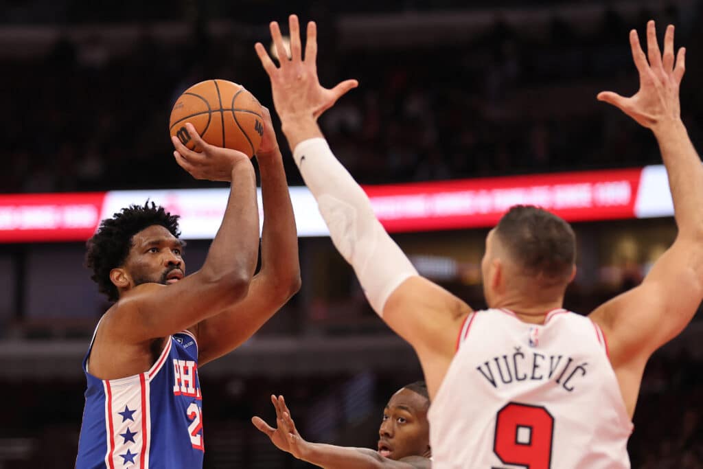 Joel Embiid #21 of the Philadelphia 76ers shoots over Nikola Vucevic #9 of the Chicago Bulls during the first half at the United Center on December 08, 2024 in Chicago, Illinois. | Michael Reaves/Getty Images/AFP