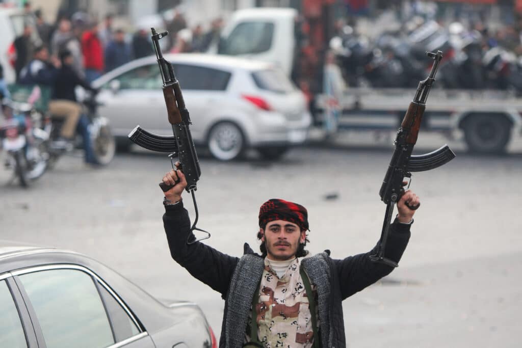 An anti-government fighter celebrates at Umayyad Square in Damascus on December 8, 2024. - Celebrations erupted around Syria and crowds ransacked President Bashar al-Assad's luxurious home on December 8 after Islamist-led rebels swept into Damascus and declared he had fled the country, in a spectacular end to five decades of Baath party rule. | Photo by Bakr AL KASSEM / AFP