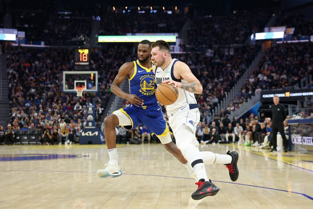 Luka Doncic #77 of the Dallas Mavericks is guarded by Andrew Wiggins #22 of the Golden State Warriors in the first half at Chase Center on December 15, 2024 in San Francisco, California. | Photo by Ezra Shaw/Getty Images/AFP 