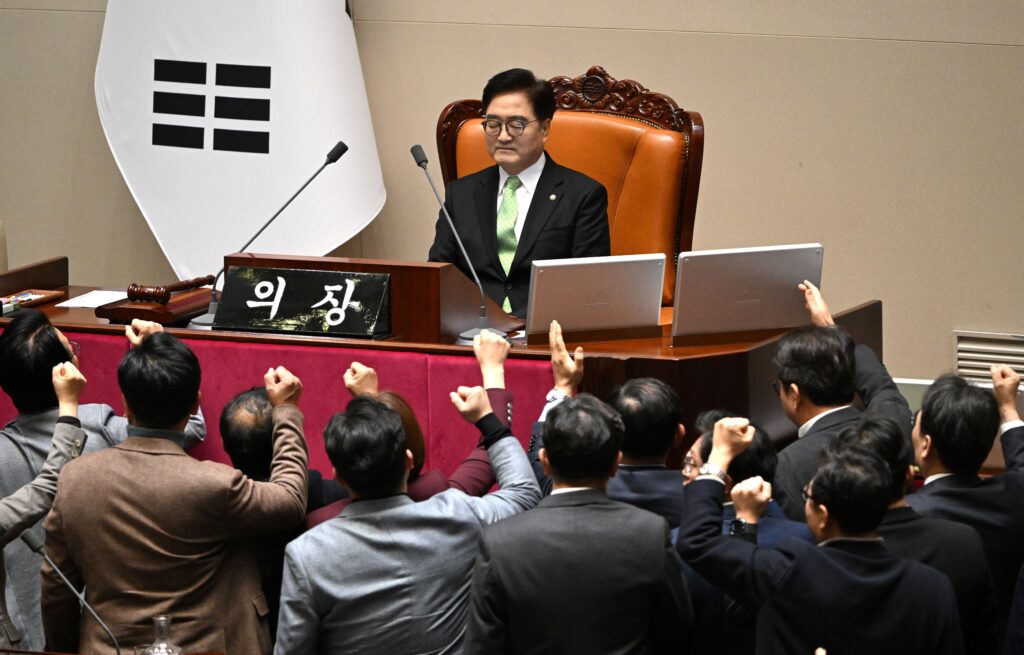 South Korea's ruling People Power Party lawmakers (bottom) argue to National Assembly Speaker Woo Won-shik (C top) during the plenary session for the impeachment vote of acting president Han Duck-soo at the National Assembly in Seoul on December 27, 2024. (Photo by JUNG YEON-JE / AFP)