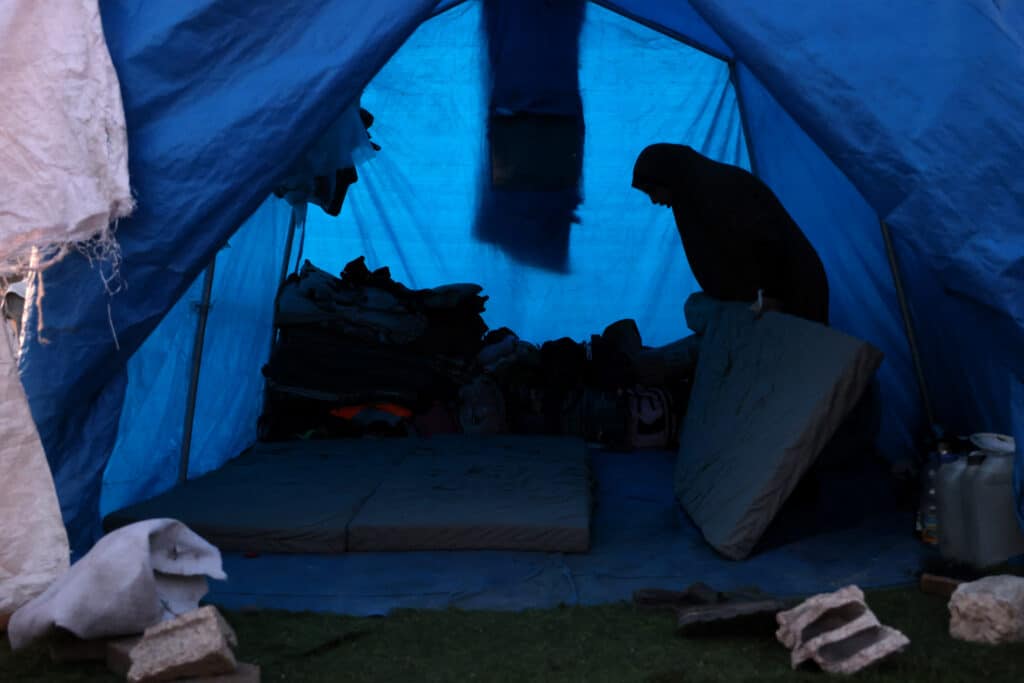 A woman prepares bedding inside a shelter at a camp for displaced Palestinians in Khan Yunis, in the southern Gaza Strip on December 29, 2024, amid the continuing war between Israel and the militant Hamas group. - Since the war between Israel and Hamas began in October last year, Gaza's 2.4 million residents have endured severe shortages of electricity, drinkable water, food and medical services. (Photo by BASHAR TALEB / AFP)