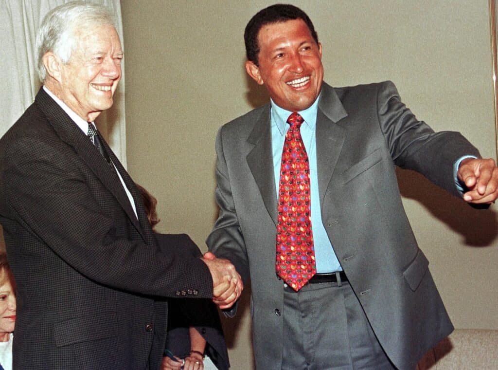 (FILES) Former US President Jimmy Carter(L) is greeted by Venezuelan presidential candidate and author of a failed 1992 attempt Hugo Chavez (R) in Caracas on November 3, 1998. | Photo by BERTRAND PARRES / AFP