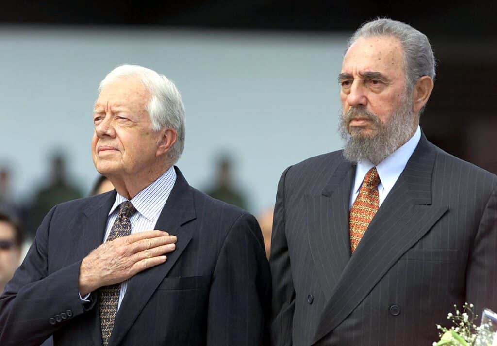 (FILES) Former US president Jimmy Carter (L) and Cuban President Fidel Castro listen to the US National Anthem after Carter's arrival at Jose Marti airport in Havana on May 12, 2002. | Photo by Adalberto ROQUE / AFP