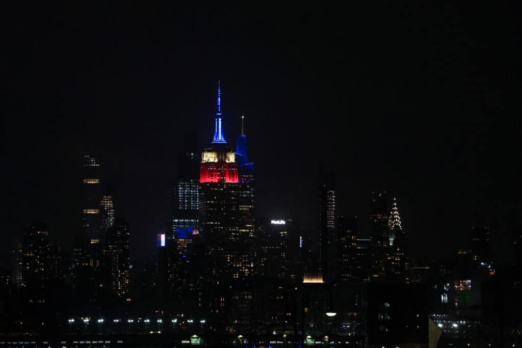 The landmark Empire State Building is illuminated in red, white and blue in honor of former president Jimmy Carter, in New York City on December 29, 2024. | Photo by CHARLY TRIBALLEAU / AFP