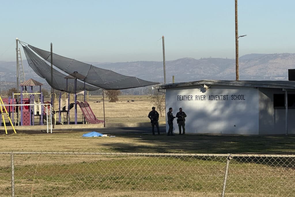  California school shooting: 2 kids wounded, gunman dead. In photo police officers are seen standing near a body covered by a tarp outside of Feather River Adventist School after a shooting Wednesday, Dec. 4, 2024, in Oroville, Calif. | Michael Weber/The Chico Enterprise-Record via AP