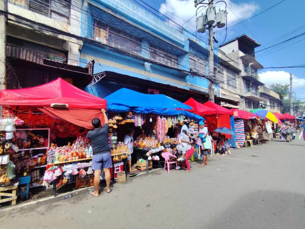 Religious icon vendor dismayed over relocation of stall. Due to the heat, a vendor attaches a cloth to his stall to protect himself and his items from the sun. | CDN Digital photo by Shannah Rose Pardo