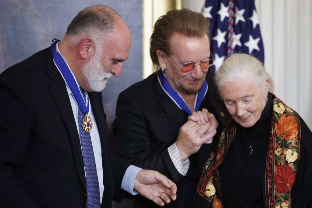 Chef Jose Andres (from left), and U2 singer Bono help ethologist and conservationist Dr. Jane Goodall ahead of her reception of the Presidential Medal of Freedom by U.S. President Joe Biden in the East Room of the White House on January 4, 2025 in Washington, DC. President Biden is awarding 19 recipients with the nation's highest civilian honor. | Tom Brenner/Getty Images/AFP