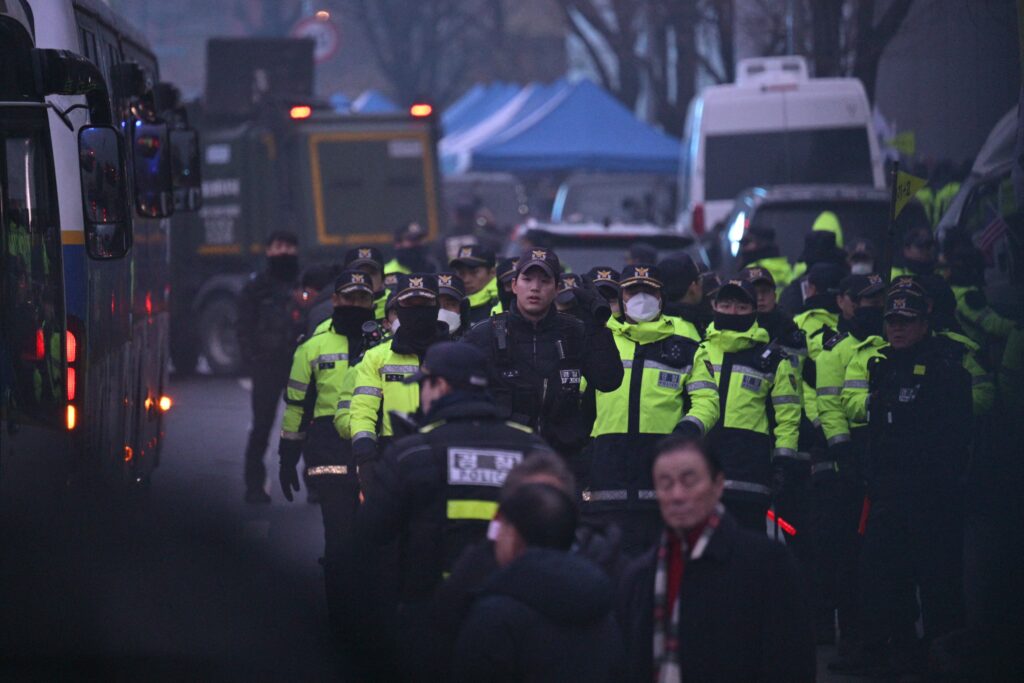 Police are seen between their parked vehicles on the road outside the residence of South Korea's impeached President Yoon Suk Yeol in Seoul early on January 6, 2025.| Photo by ANTHONY WALLACE / AFP