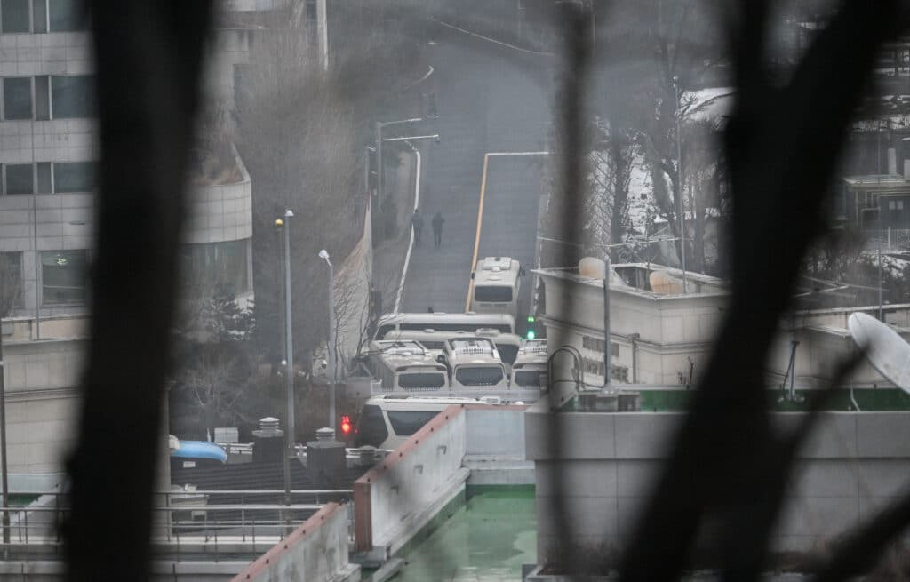 Security personnel walk on the road with buses blocking an entrance gate to protect impeached South Korean President Yoon Suk Yeol from a possible second arrest attempt by the Corruption Investigation Office for High-ranking Officials inside the compound of the presidential residence in Seoul on January 6, 2025. | Photo by JUNG YEON-JE / AFP