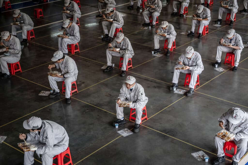 (FILES) This photo taken on March 23, 2020 shows employees eating during lunch break at an auto plant of Dongfeng Honda in Wuhan in China's central Hubei province. | Photo by AFP [FILE PHOTO]