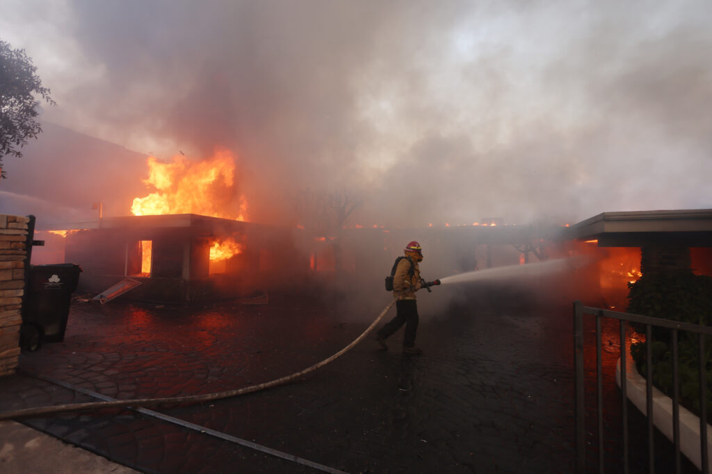 A firefighter douses the flames around a home destroyed by the wind-driven Palisades Fire in Pacific Palisades, California, January 7, 2025. | Photo by David Swanson / AFP