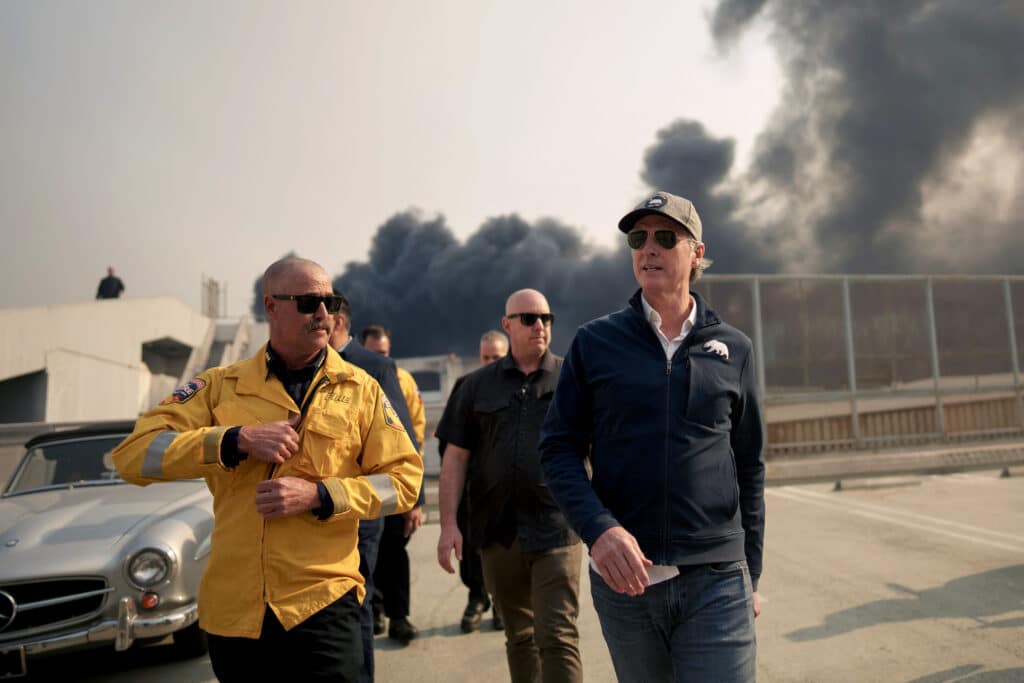 California Governor Gavin Newsom (R) tours the downtown business district of Pacific Palisades as the Palisades Fire continues to burn on January 8, 2025 in Los Angeles, California.|  Eric Thayer/Getty Images/AFP 