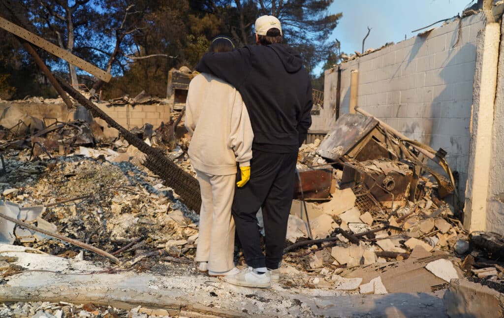 Los Angeles investigates fire blame as curfew enforced. Kyle Kucharski hugs his partner Nicole Perri as they stand on the ruins of their house destroyed by the Palisades Fire in the Pacific Palisades neighborhood of Los Angeles, California on January 10, 2025. | Photo by Cecilia SANCHEZ / AFP