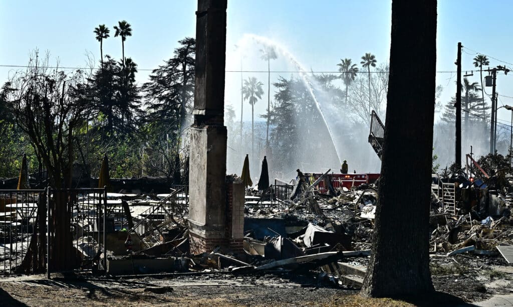 Firefighters working on the grounds of the fire-ravaged Saint Mark's Episcopal Chuch water down smoky embers from its neighboring fire-ravaged Sahag Mesrob Armenian Christian School on January 13, 2025 in Altadena, California, where the devastating Eaton Fire caused widespread damage. | Photo by Frederic J. BROWN / AFP