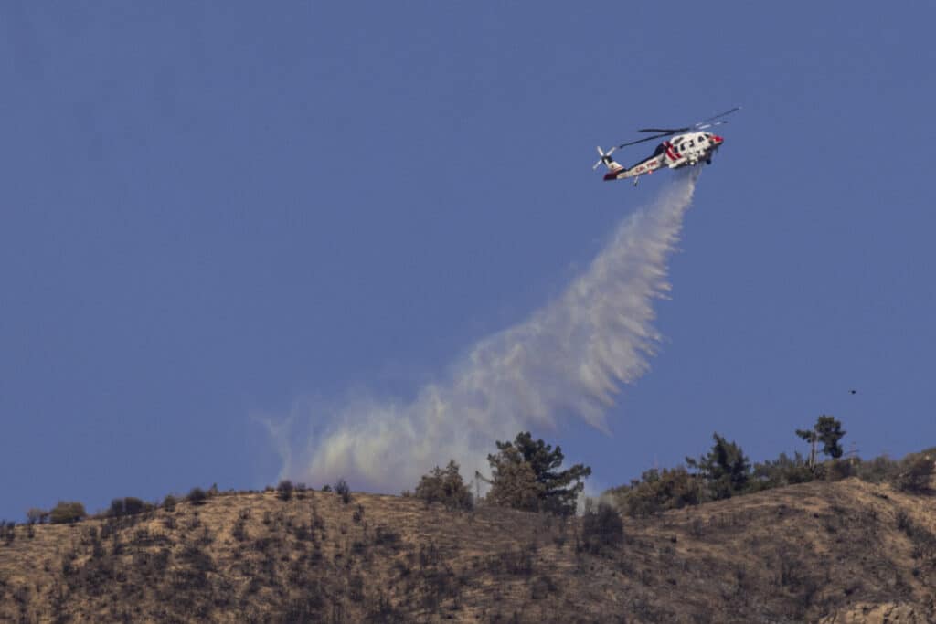 Los Angeles: Stronger winds threaten to fan wildfires ravaging area. A firefighting helicopter drops water on the Eaton Fire buring in the Angeles National Forest, North of Altadina, California, on January 13, 2025. | Photo by ETIENNE LAURENT / AFP