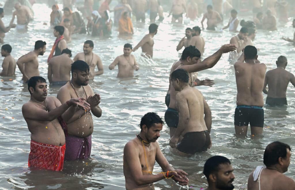 Hindu pilgrims take part in a mass bathing ritual in Sangam, the confluence of Ganges, Yamuna, and mythical Saraswati rivers, during Shahi Snan or 'royal bath,' to mark the Maha Kumbh Mela festival, in Prayagraj on January 14, 2025. | Photo by R.Satish BABU / AFP