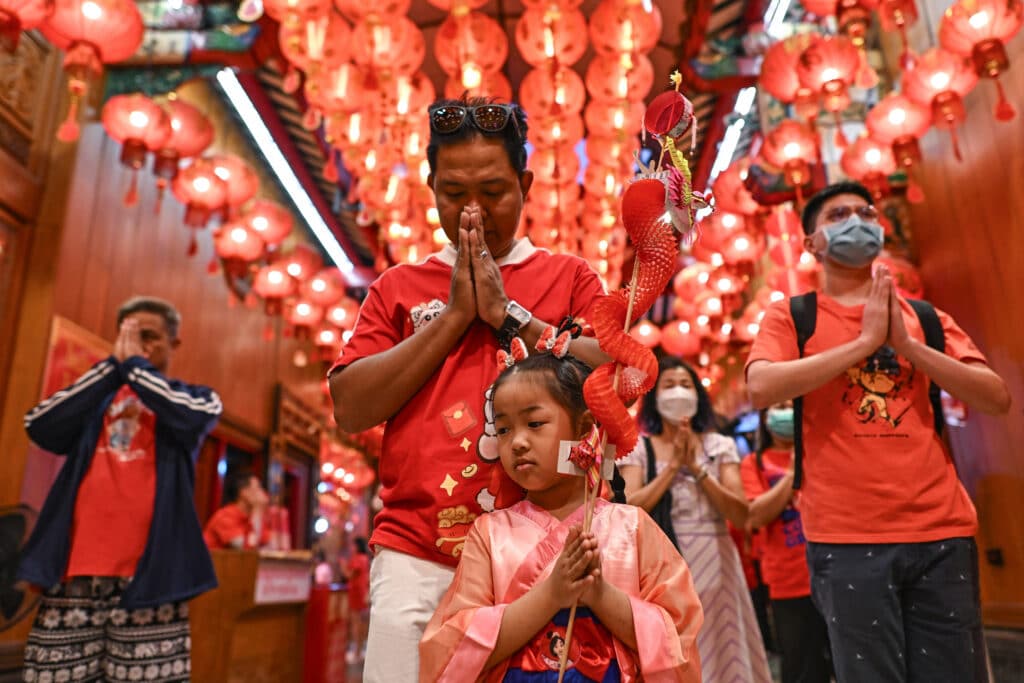 People offer prayers at the Wat Mangkon Kamalawat temple in the Chinatown area of Bangkok of Bangkok on January 28, 2025, on the eve of the Lunar New Year of the Snake. (Photo by MANAN VATSYAYANA / AFP)