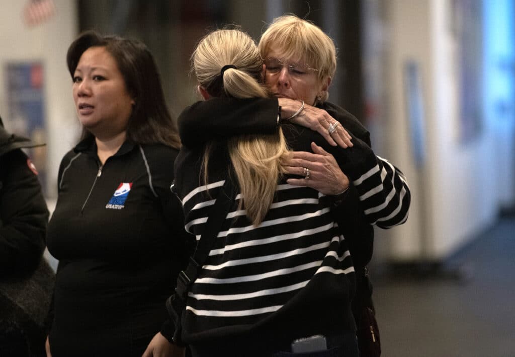 Members of the skating community embrace at the Skating Club of Boston where a memorial has been set up, to remember six Boston area skaters and their family members and coaches that perished on American Airlines flight 5342, in Norwood, Massachusetts on January 30, 2025. | Photo by Joseph Prezioso / AFP