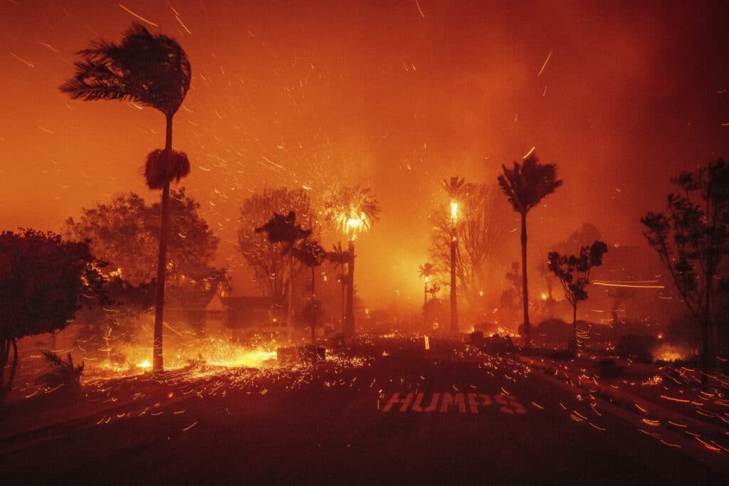 Los Angeles wildfires burn out of control, 2 dead as thousands flee. The Palisades Fire ravages a neighborhood amid high winds in the Pacific Palisades neighborhood of Los Angeles, Tuesday, Jan. 7, 2025. (AP Photo/Ethan Swope)