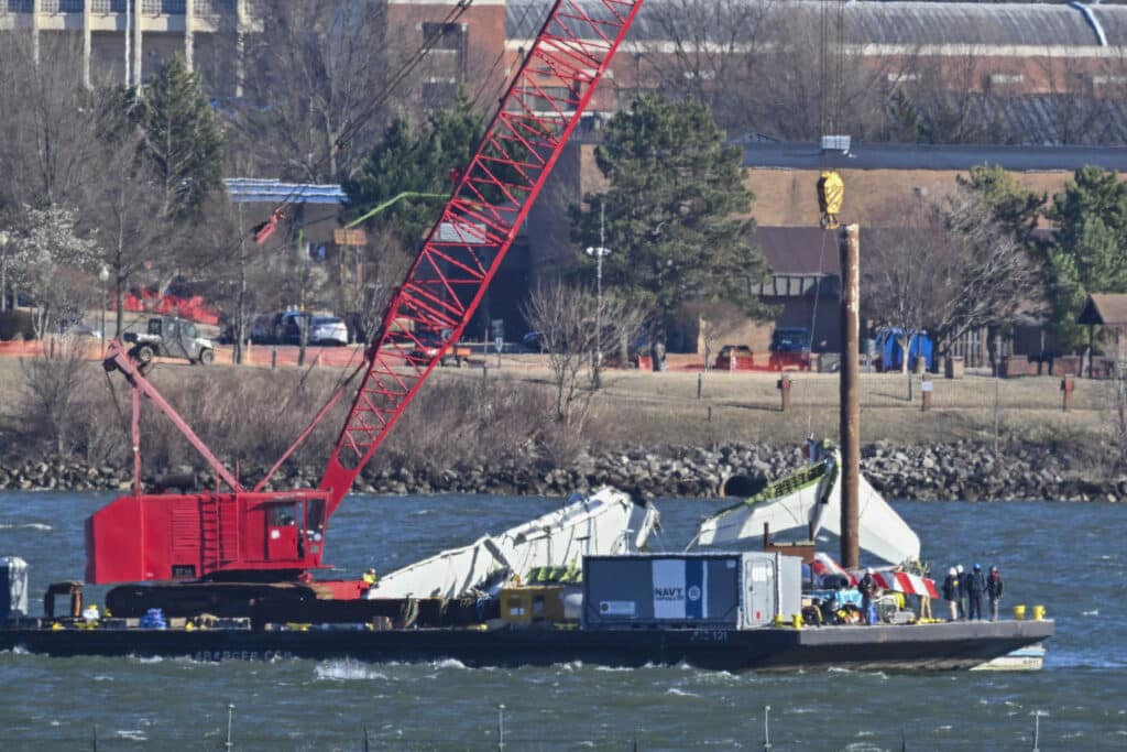 US Navy recovery teams lift the back wing section of an American Airliners plane from the Potomac in Arlington, Virginia on February 4, 2025. Operations to salvage the wreckage from a deadly collision between a US Army helicopter and a passenger jet continued as rescuers said 55 victims had so far been identified. (Photo by ROBERTO SCHMIDT / AFP)