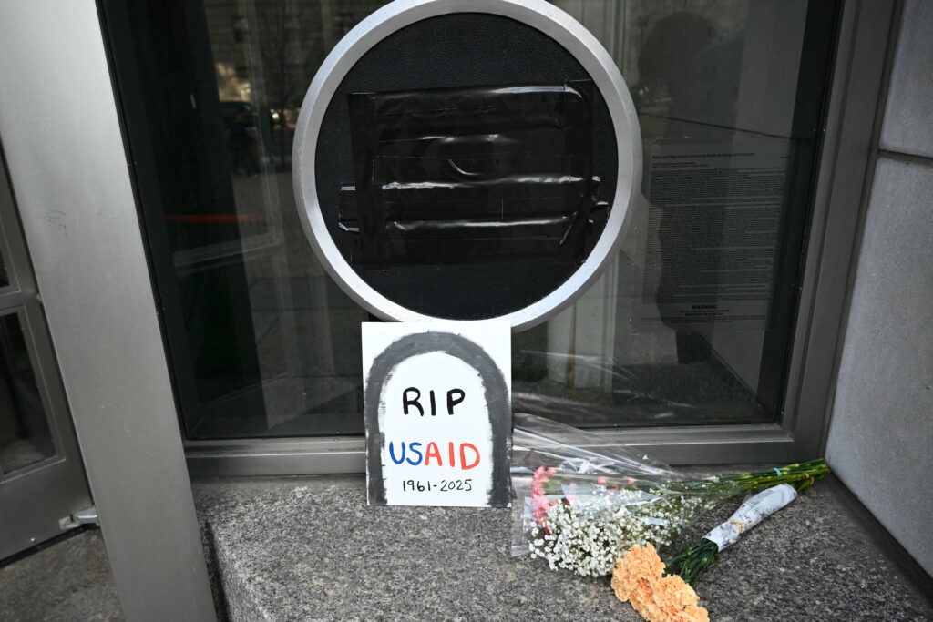 Trump administration: It's cutting 90% of USAID foreign aid contracts. Photo shows Tributes placed beneath the covered seal of the US Agency for International Development (USAID) at their headquarters in Washington, DC, on February 7, 2025. US President Donald Trump on February 7, 2025 called for USAID to be shuttered, escalating his unprecedented campaign to dismantle the humanitarian agency. (Photo by Mandel NGAN / AFP)